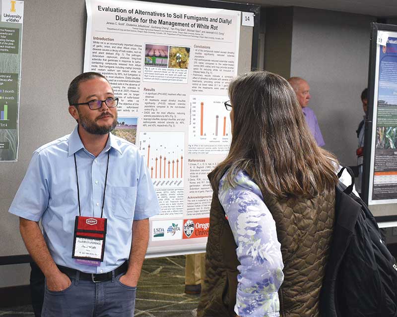 Jeremiah Dung with Oregon State University reviews a poster presentation on white rot management with an attendee. Researchers displayed 30 posters throughout the conference.