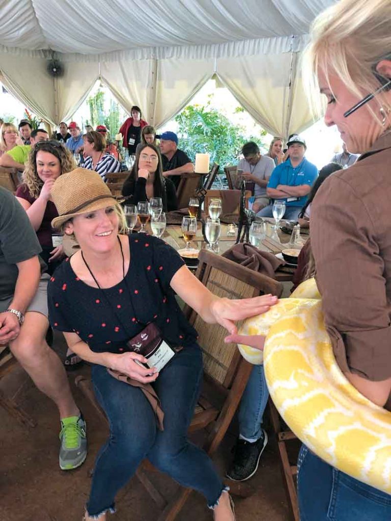 Kimi Maag with Jamieson Produce in Vale, Ore., pets a snake during the NOA tour of NGALA Wildlife Preserve in Naples, Fla.