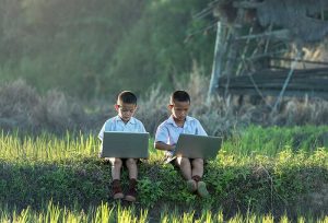 children in field on laptops
